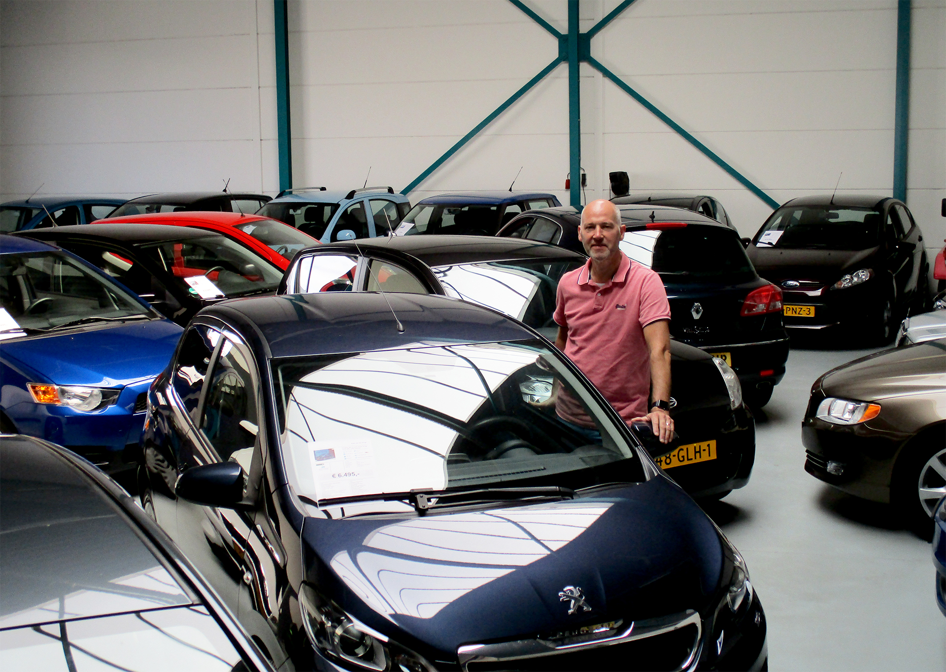 Alfons van der Krogt tussen zijn auto's in de showroom